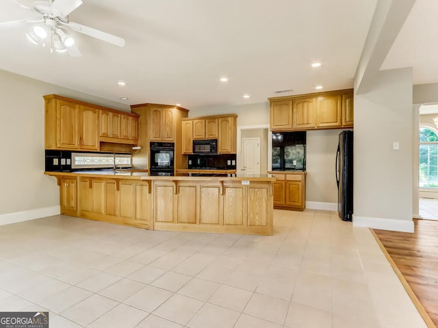 kitchen featuring ceiling fan, tasteful backsplash, kitchen peninsula, light tile patterned floors, and black appliances