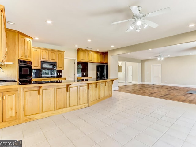 kitchen with kitchen peninsula, ceiling fan, black appliances, light hardwood / wood-style flooring, and tile counters