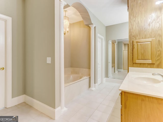 bathroom with tile patterned flooring, a washtub, vanity, and decorative columns