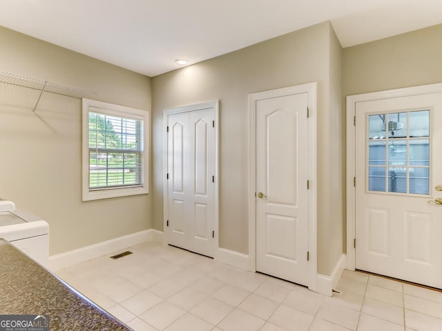 tiled foyer entrance with washer / dryer