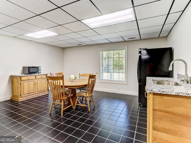 tiled dining space with a drop ceiling and sink