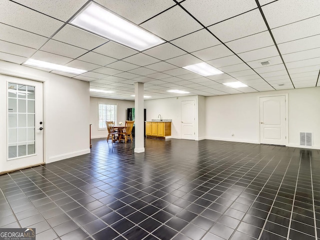 basement featuring a paneled ceiling and dark tile patterned flooring