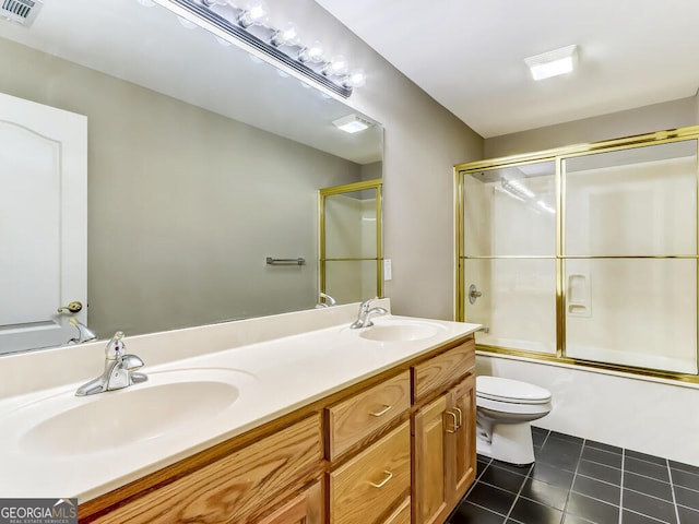 full bathroom with tile patterned flooring, vanity, enclosed tub / shower combo, and toilet