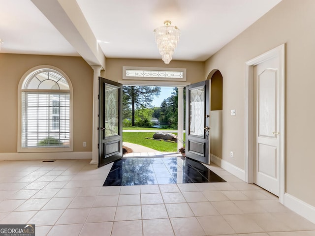 foyer featuring a chandelier, light tile patterned floors, and plenty of natural light