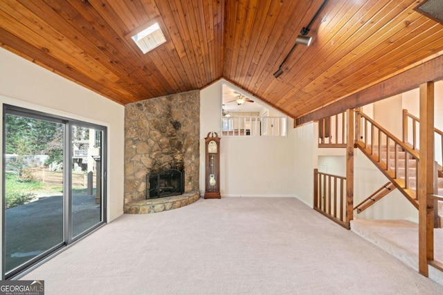 unfurnished living room featuring ceiling fan, lofted ceiling with skylight, carpet floors, and wood ceiling