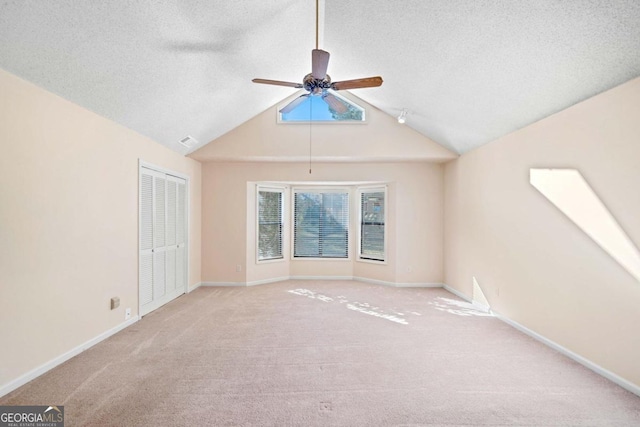 spare room featuring a textured ceiling, light carpet, ceiling fan, and lofted ceiling