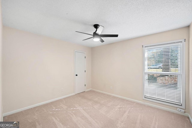 spare room featuring ceiling fan, light colored carpet, and a textured ceiling