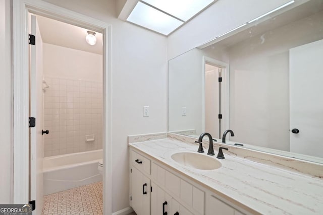 full bathroom with vanity, a skylight, toilet, and tiled shower / bath