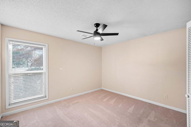 carpeted empty room featuring ceiling fan and a textured ceiling