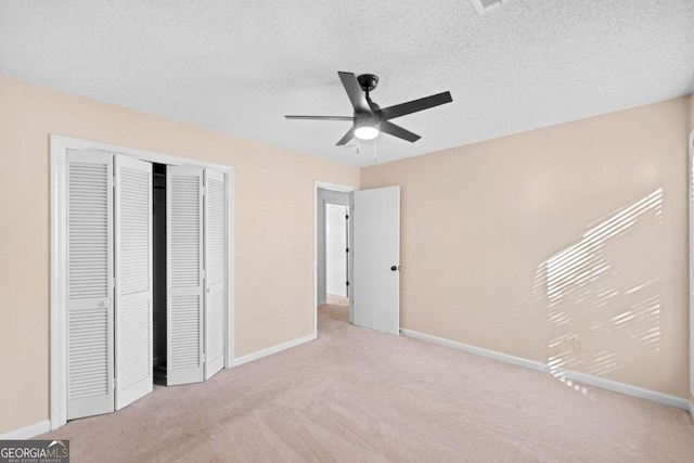 unfurnished bedroom featuring ceiling fan, light colored carpet, and a textured ceiling