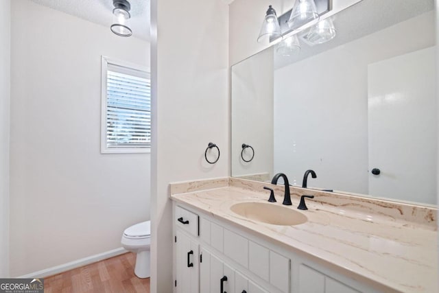 bathroom featuring vanity, wood-type flooring, a textured ceiling, and toilet