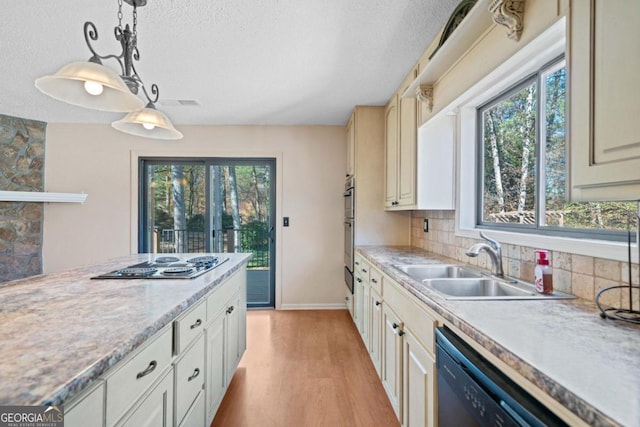 kitchen featuring sink, stainless steel gas cooktop, decorative light fixtures, light hardwood / wood-style floors, and dishwashing machine