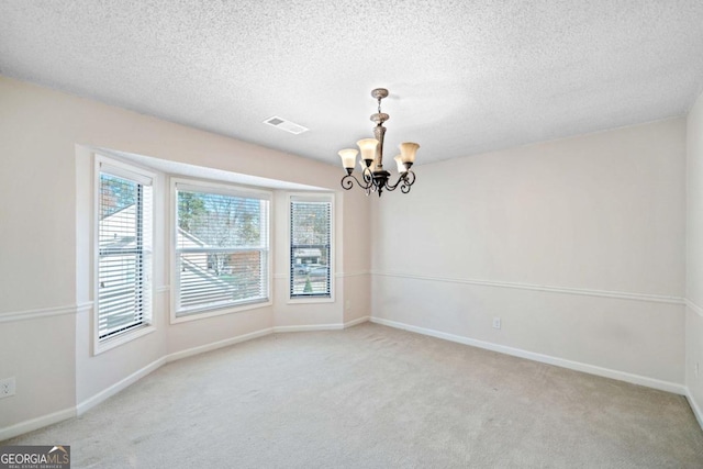 carpeted spare room featuring a textured ceiling and a notable chandelier