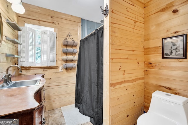 bathroom featuring vanity, wood walls, and toilet