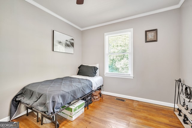 bedroom with hardwood / wood-style flooring, ceiling fan, and crown molding