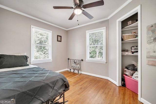 bedroom with hardwood / wood-style floors, ceiling fan, crown molding, and multiple windows