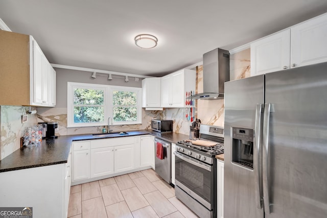 kitchen with tasteful backsplash, wall chimney exhaust hood, stainless steel appliances, sink, and white cabinets