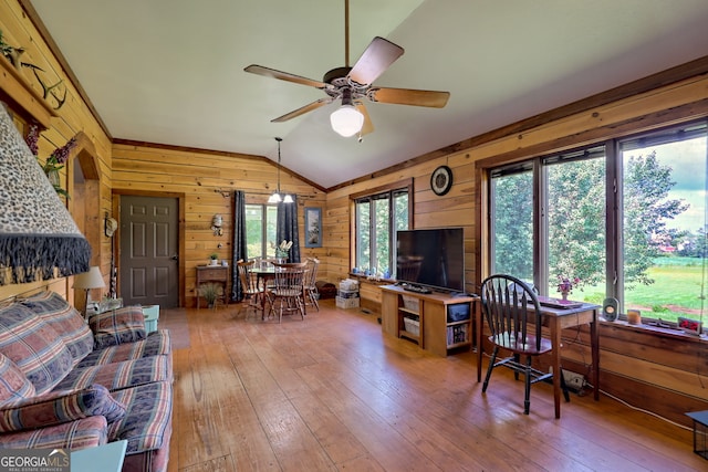 living room featuring hardwood / wood-style floors, wooden walls, vaulted ceiling, and a healthy amount of sunlight