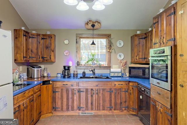 kitchen with lofted ceiling, black appliances, sink, hanging light fixtures, and light tile patterned floors