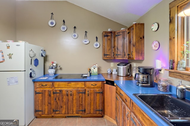 kitchen featuring black electric stovetop, vaulted ceiling, sink, light tile patterned floors, and white refrigerator