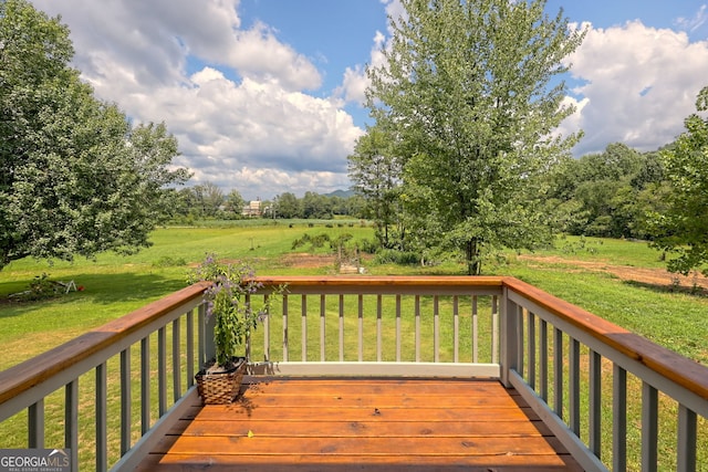 wooden deck featuring a rural view and a lawn