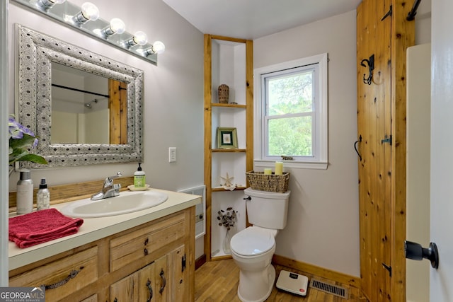 bathroom with walk in shower, vanity, wood-type flooring, and toilet