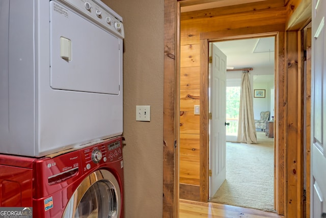 laundry area with stacked washing maching and dryer and wood-type flooring