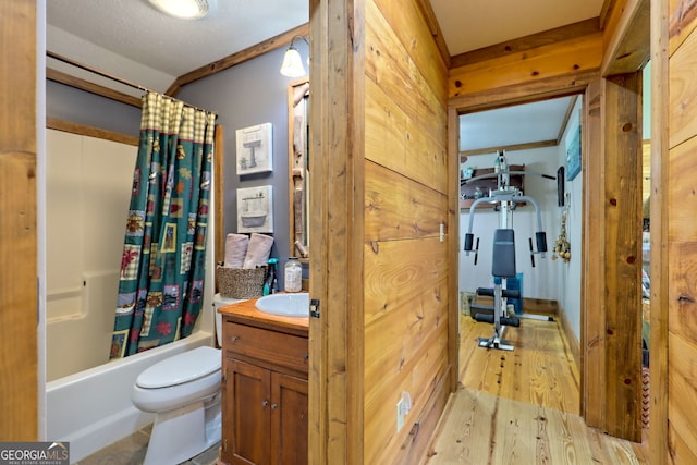 full bathroom with shower / tub combo, vanity, wooden walls, wood-type flooring, and toilet