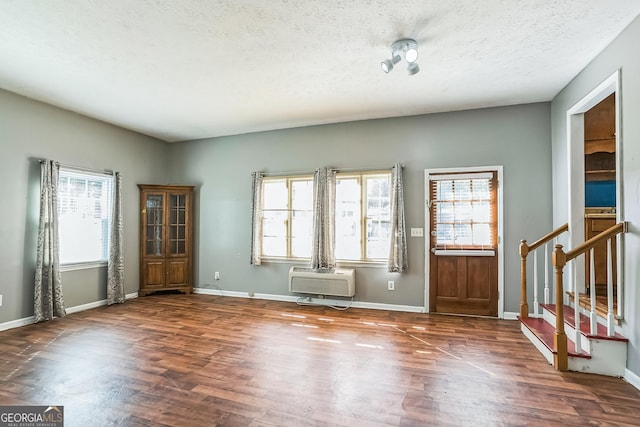 entrance foyer featuring dark hardwood / wood-style flooring, an AC wall unit, and a textured ceiling