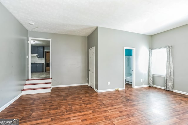 unfurnished room featuring a textured ceiling and dark hardwood / wood-style floors