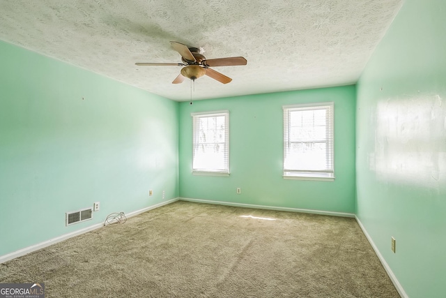 carpeted spare room featuring ceiling fan and a textured ceiling