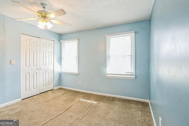 unfurnished bedroom with ceiling fan, carpet floors, and multiple windows