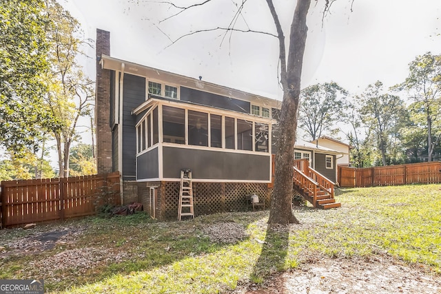 rear view of property with a lawn and a sunroom