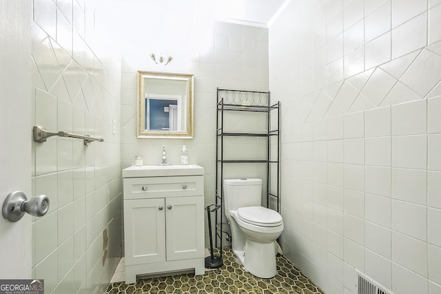 bathroom featuring vanity, tile walls, and toilet