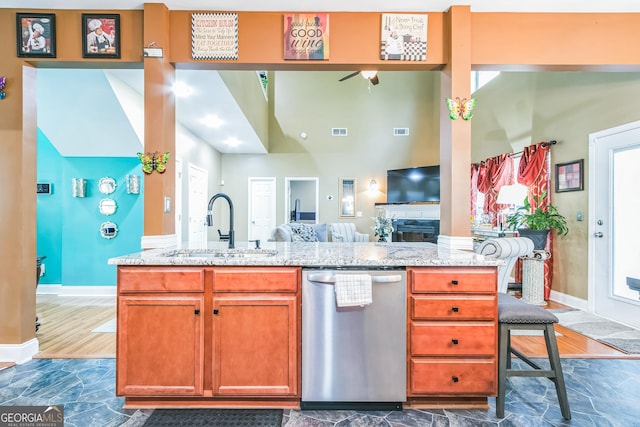 kitchen featuring light stone countertops, stainless steel dishwasher, and sink