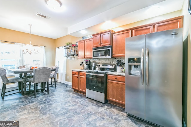 kitchen with a healthy amount of sunlight, hanging light fixtures, stainless steel appliances, a chandelier, and decorative backsplash