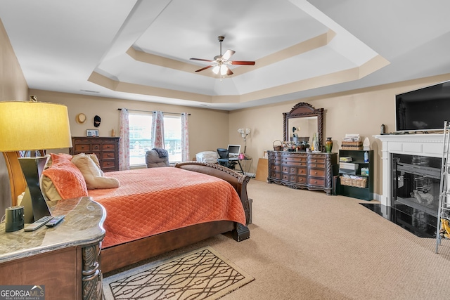 carpeted bedroom with ceiling fan and a raised ceiling