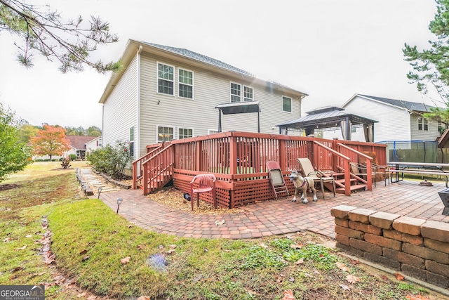 rear view of house with a patio, a deck, and a trampoline