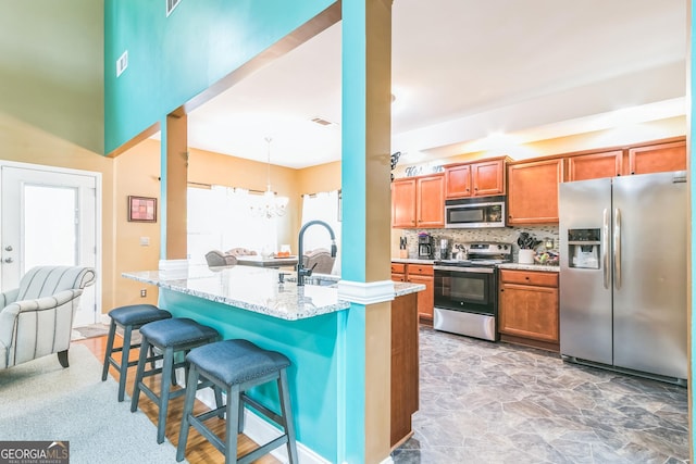 kitchen featuring sink, decorative light fixtures, a kitchen bar, kitchen peninsula, and stainless steel appliances