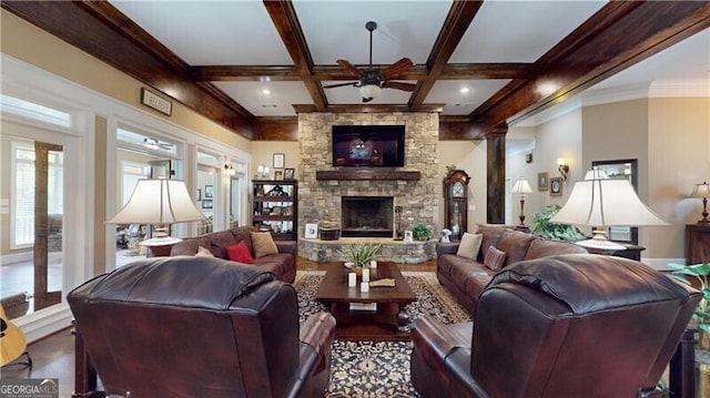 living room with beam ceiling, a stone fireplace, ceiling fan, and coffered ceiling