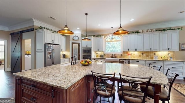 kitchen with a barn door, a large island, white cabinets, and stainless steel appliances