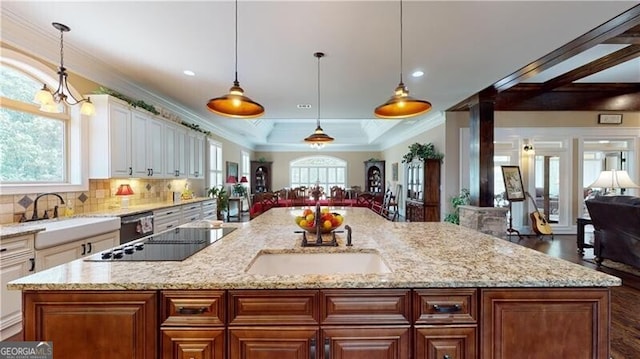 kitchen with dark hardwood / wood-style flooring, light stone countertops, a center island with sink, and pendant lighting