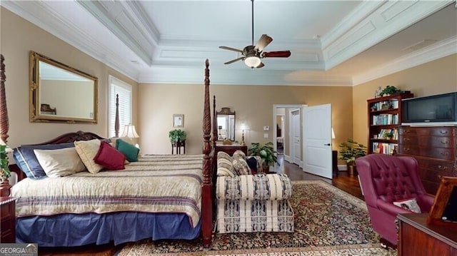 bedroom with hardwood / wood-style floors, ceiling fan, ornamental molding, and a tray ceiling