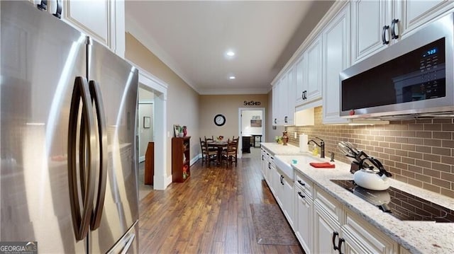 kitchen with white cabinetry, sink, light stone counters, dark hardwood / wood-style floors, and appliances with stainless steel finishes