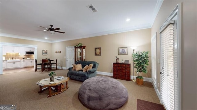 carpeted living room with ornamental molding, ceiling fan, and a healthy amount of sunlight