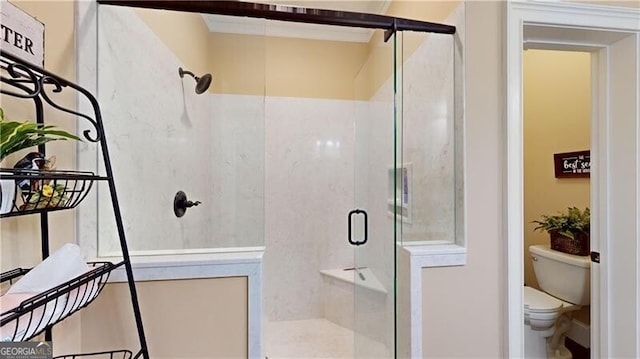 bathroom featuring toilet and a shower with shower door