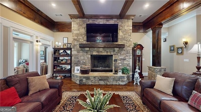 living room with decorative columns, a stone fireplace, ornamental molding, and hardwood / wood-style flooring