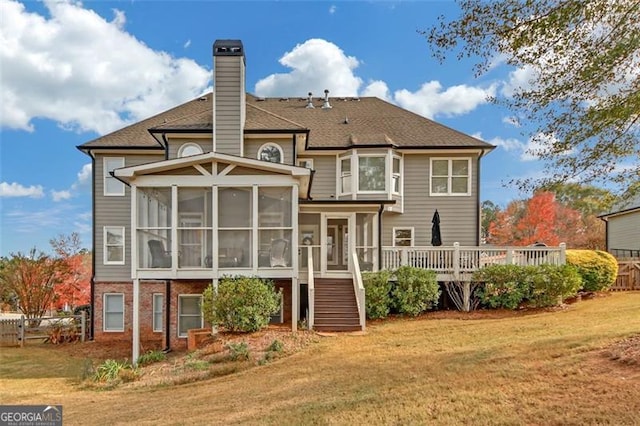 back of property featuring a wooden deck, a sunroom, and a yard