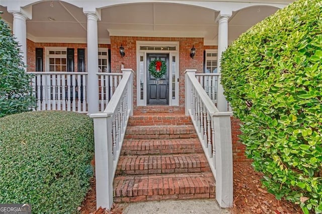 entrance to property featuring covered porch and brick siding