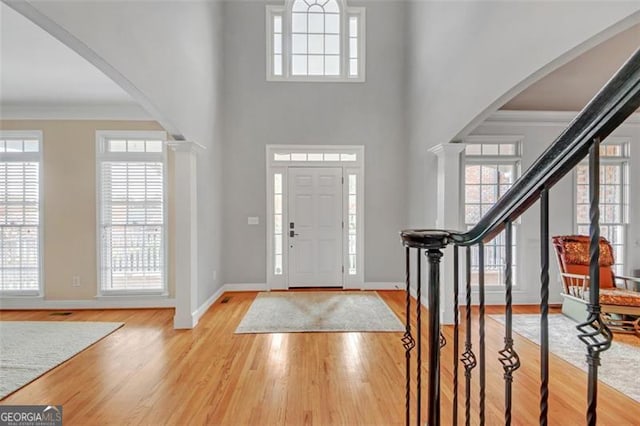 entrance foyer with arched walkways, stairway, and wood finished floors